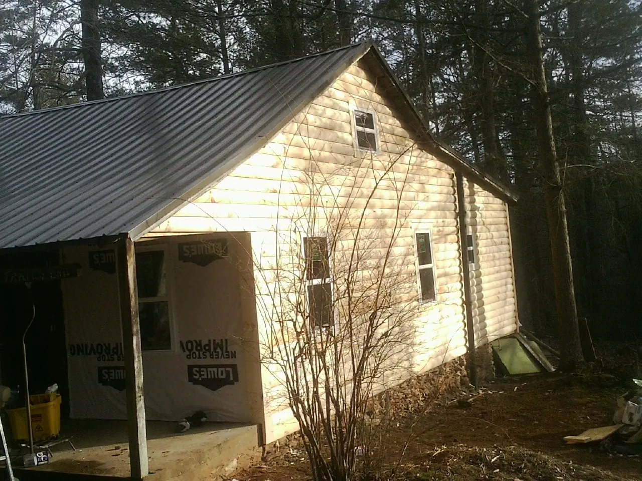 Log siding gable end under a dark metal roof edge in Manly