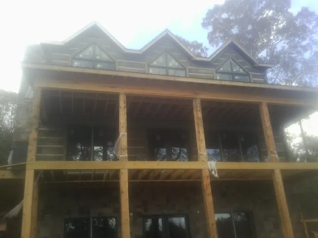 Dormers and porch framing on a large log home under construction — Roof Coating work by our crew in Manly