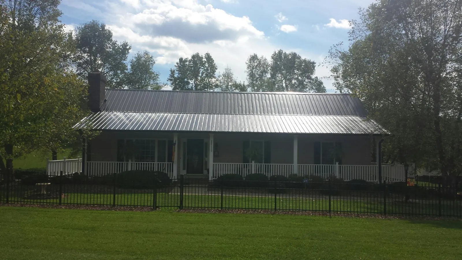 Gray metal roof on a brick ranch with a full width front porch — Gutter Guard Installation work by our crew in Manly