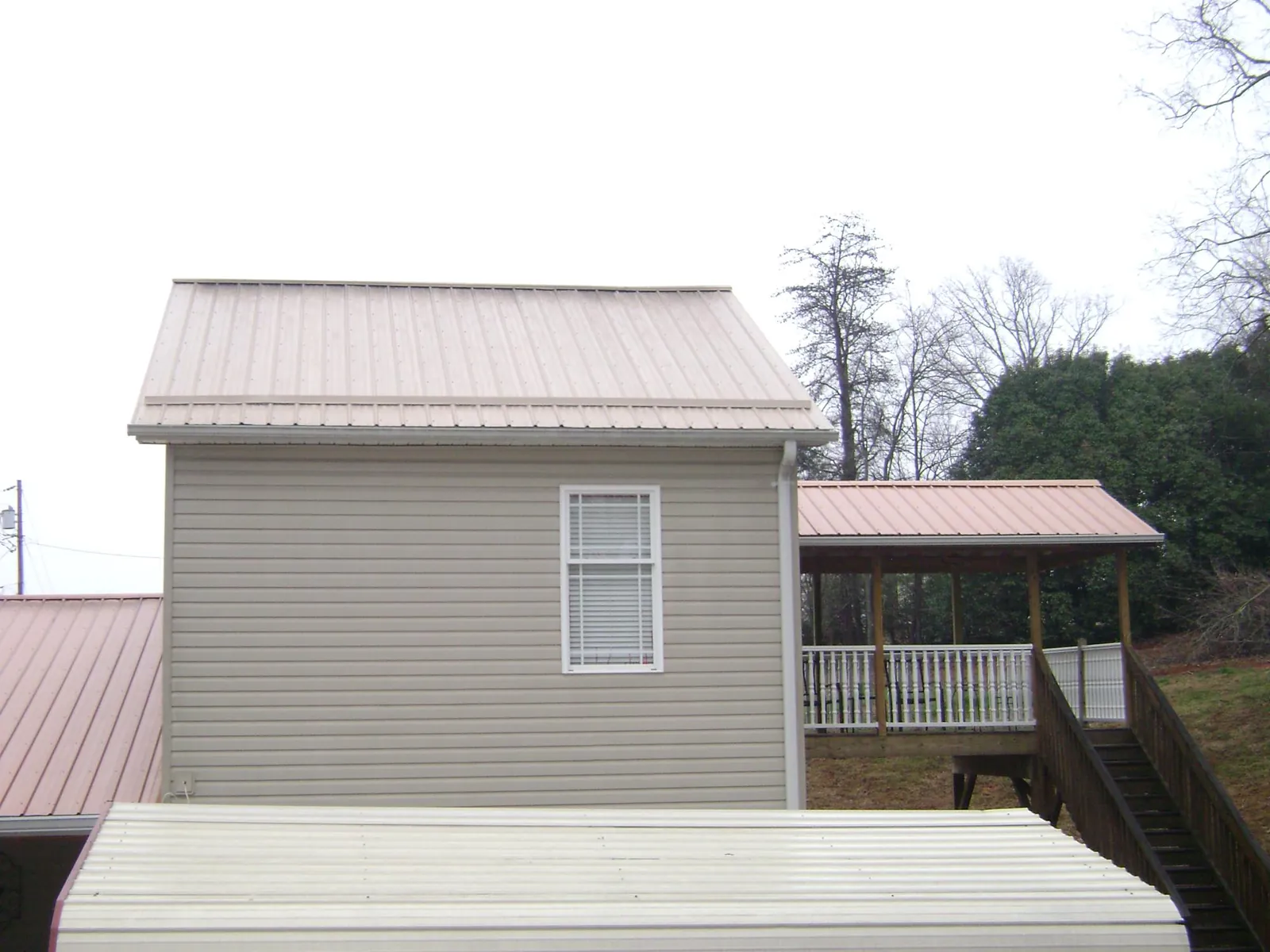 Tan metal roofs on a two story addition and attached porch, from a Roof Replacement job in Manly