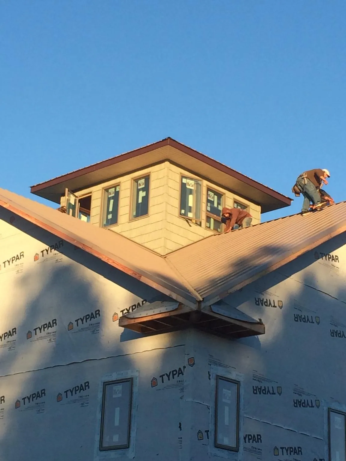 Roofers working around a rooftop cupola on a new metal roof at sunset — Roof Waterproofing in Manly by Roofing Brothers
